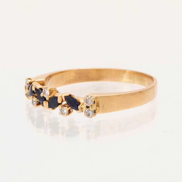 An 18K gold ring set with marquise cut, likely,  sapphires and round brilliant cut diamonds.