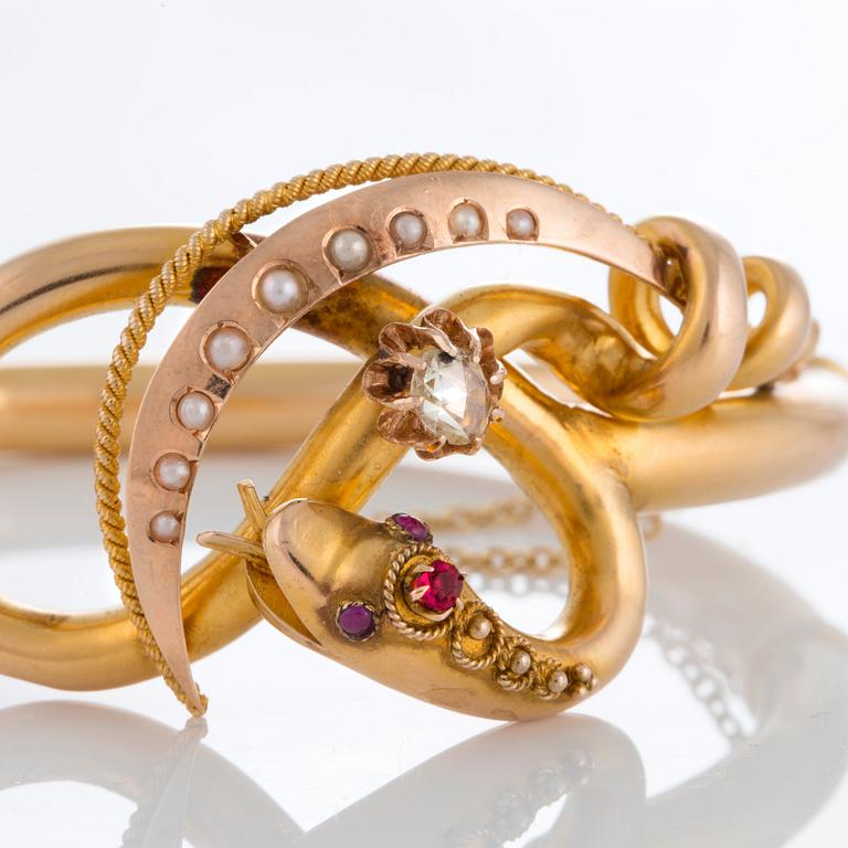 A snake bangle in 14K gold set with a rose-cut diamond, pearls and cabochon-cut rubies.