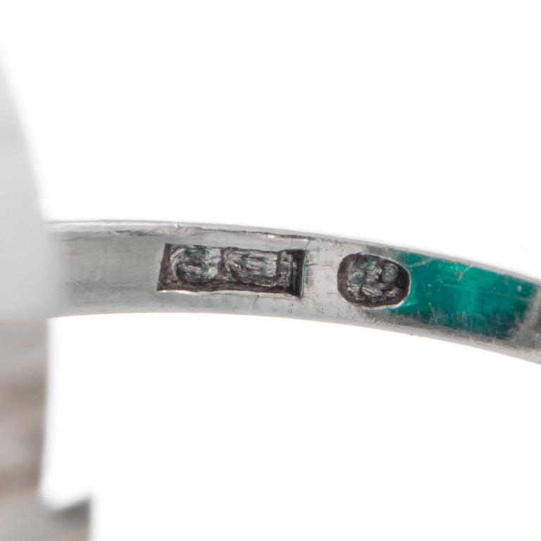 A platinum ring set with a cabochon-cut emerald ca 7 cts and brilliant and baguette-cut diamonds.