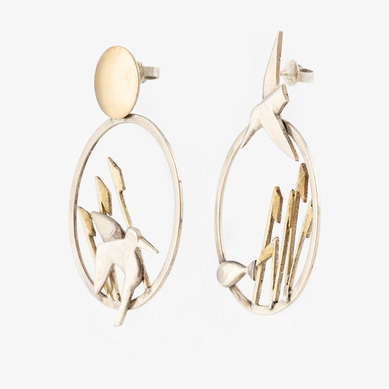 A pair of earrings featuring birds and fish, silver with gold detail.