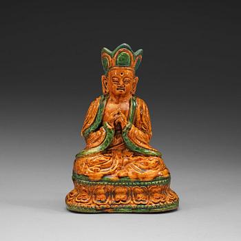 A yellow and green glazed pottery figure of a seated Buddha, Ming dynasty, 17th century.