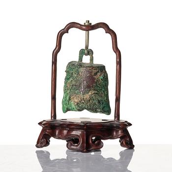 An archaic bronze bell in a wooden stand.