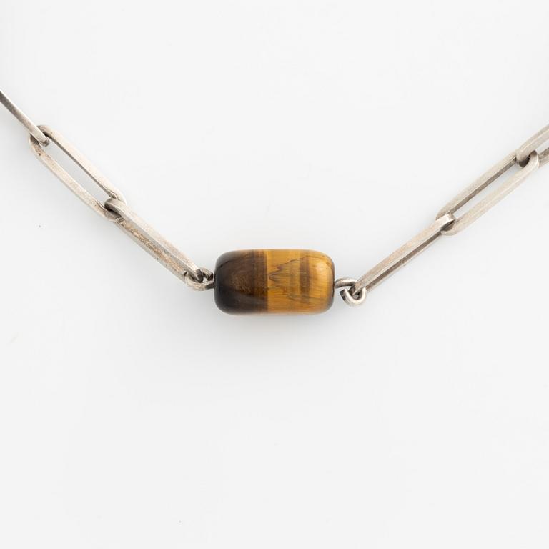 Birger Haglund, a silver and tiger's eye necklace.