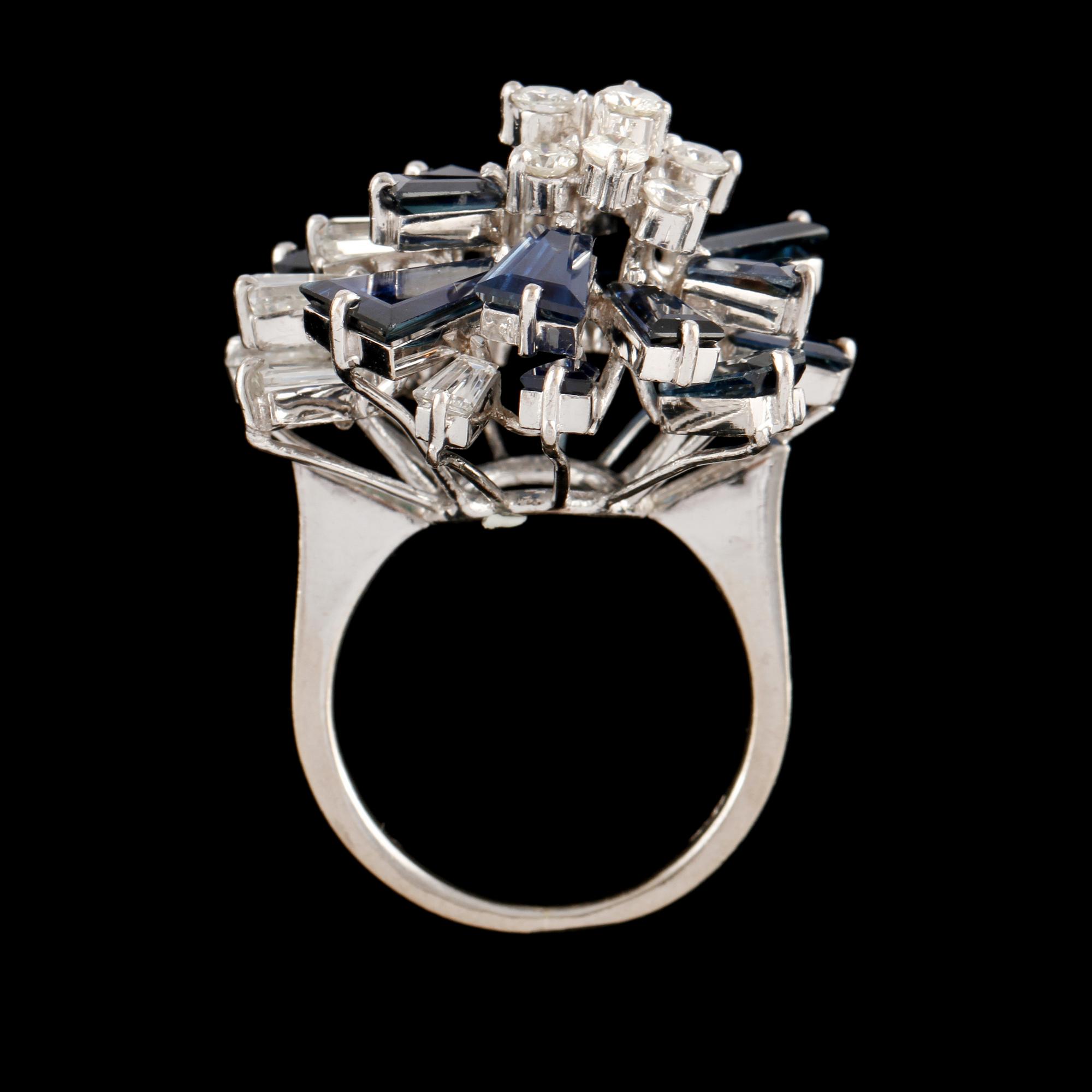 RING, 18K vitguld med 16 trapetsslipade blå safirer samt 5 trapets och 10 briljantslipade diamanter. Vikt 9,4 g.