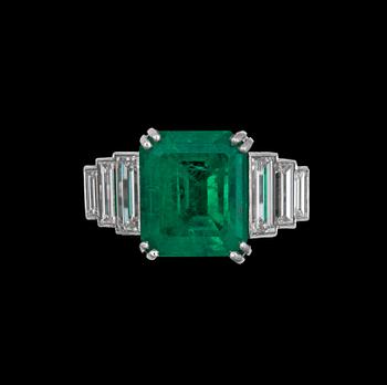 1045. A step cut emerald app 6.00 cts, flanked by diamonds.