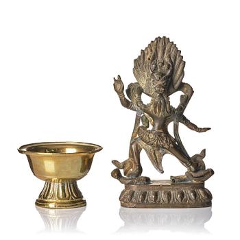 1081. A bronze deity and a brass sacrificial bowl, Tibet, circa 1900.