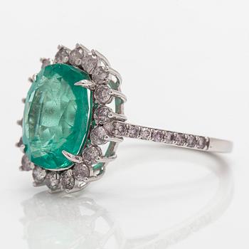 A 14K white gold ring, with an oval-cut emerald and diamonds. With IGI certificate.