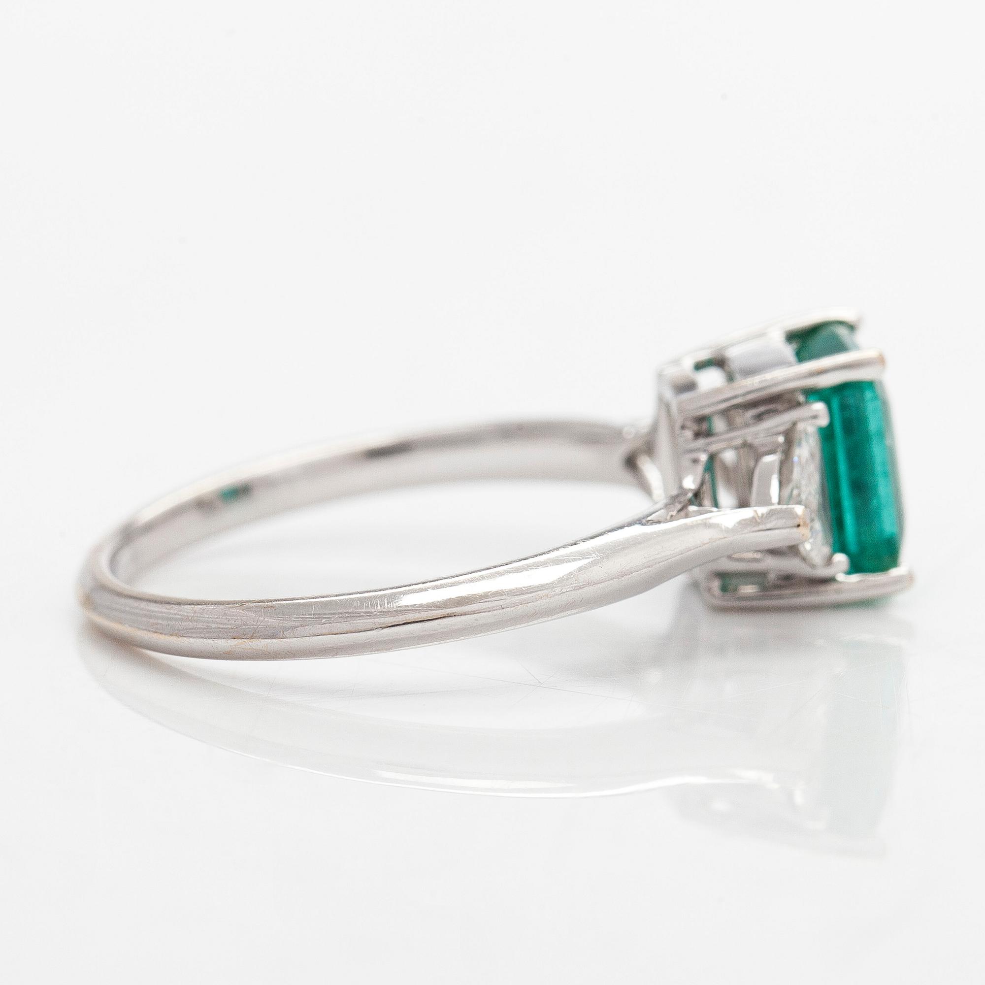 An 18K white gold ring, set with a Zambian emerald and trillion-cut diamonds.