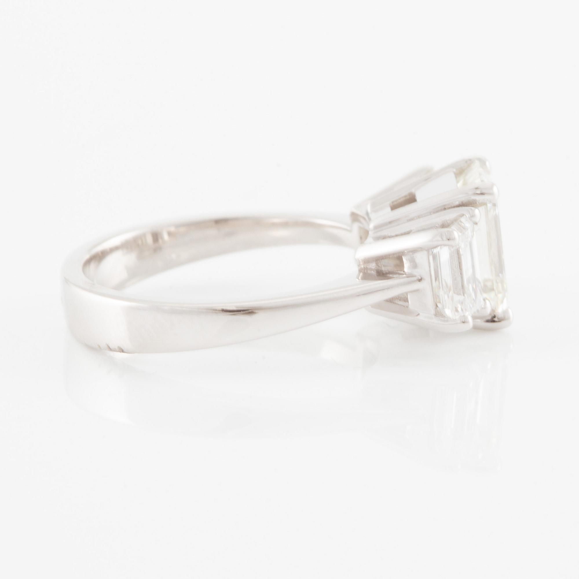 An 18K white gold ring set with three emerald-cut diamonds.