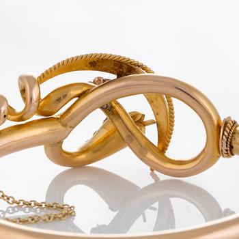 A snake bangle in 14K gold set with a rose-cut diamond, pearls and cabochon-cut rubies.