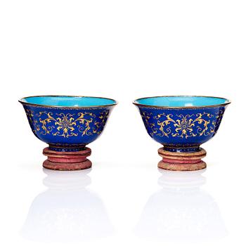 1123. A pair of gilt decorated blue ground painted enamel bowls, Qianlong four character seal mark and period (1736-95).