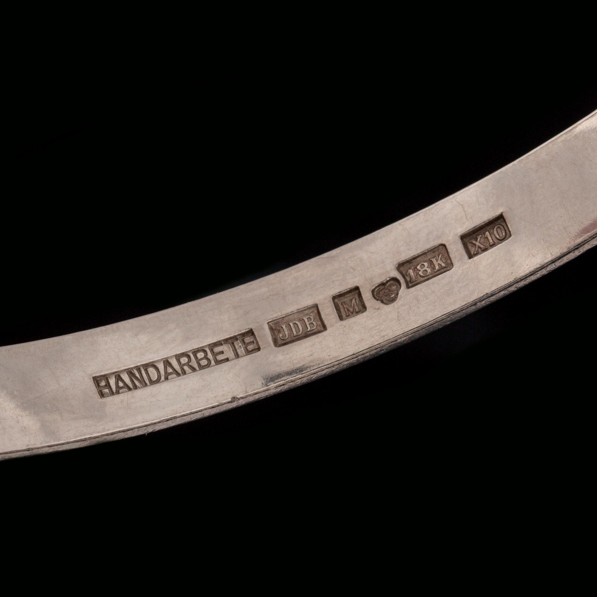 ARMRING, 18 k vitguld med briljantslipad diamant ca 0.05 ct samt 2 fasettslipade safirer. Vikt ca 33 g.