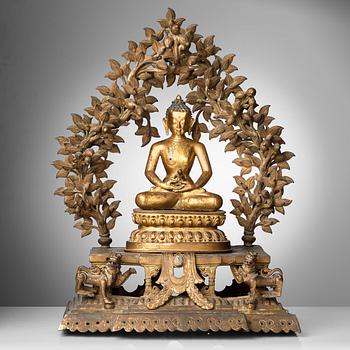 502. A large Nepalese gilt bronze buddha on a throne with mandorla, 18/19th Century.