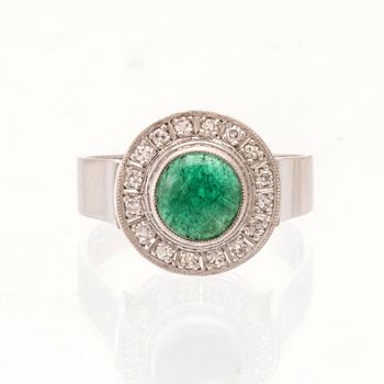 An 18K white gold ring set with a cabochon-cut emerald and round single-cut diamonds.