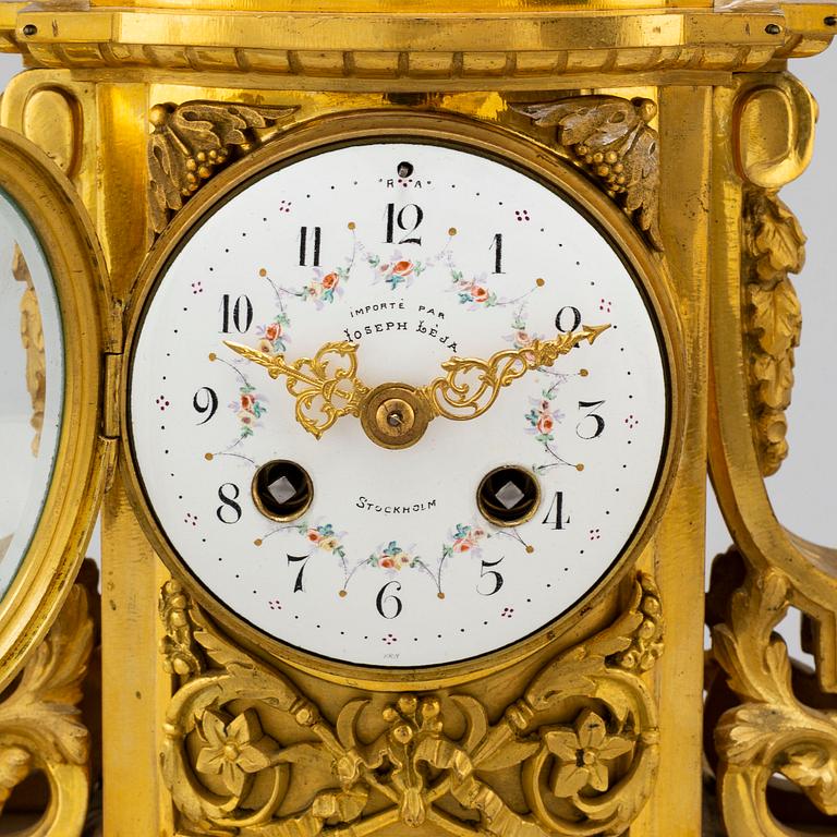 A late 19th century pendulum clock and a pair of candelabras.