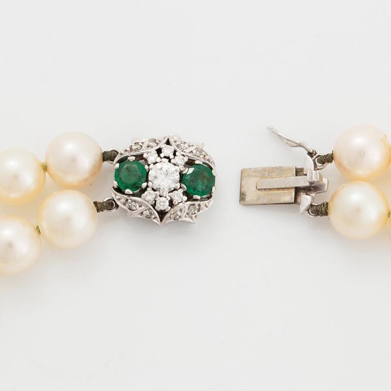 A two strand cultured pearl necklace clasp in 18K white gold set with a faceted emerald.