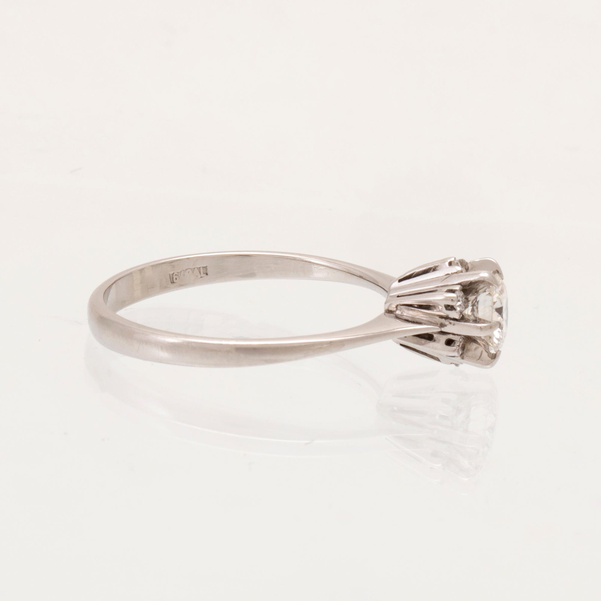 An 18K white gold ring set with a round brilliant cut diamond and single cut diamonds.