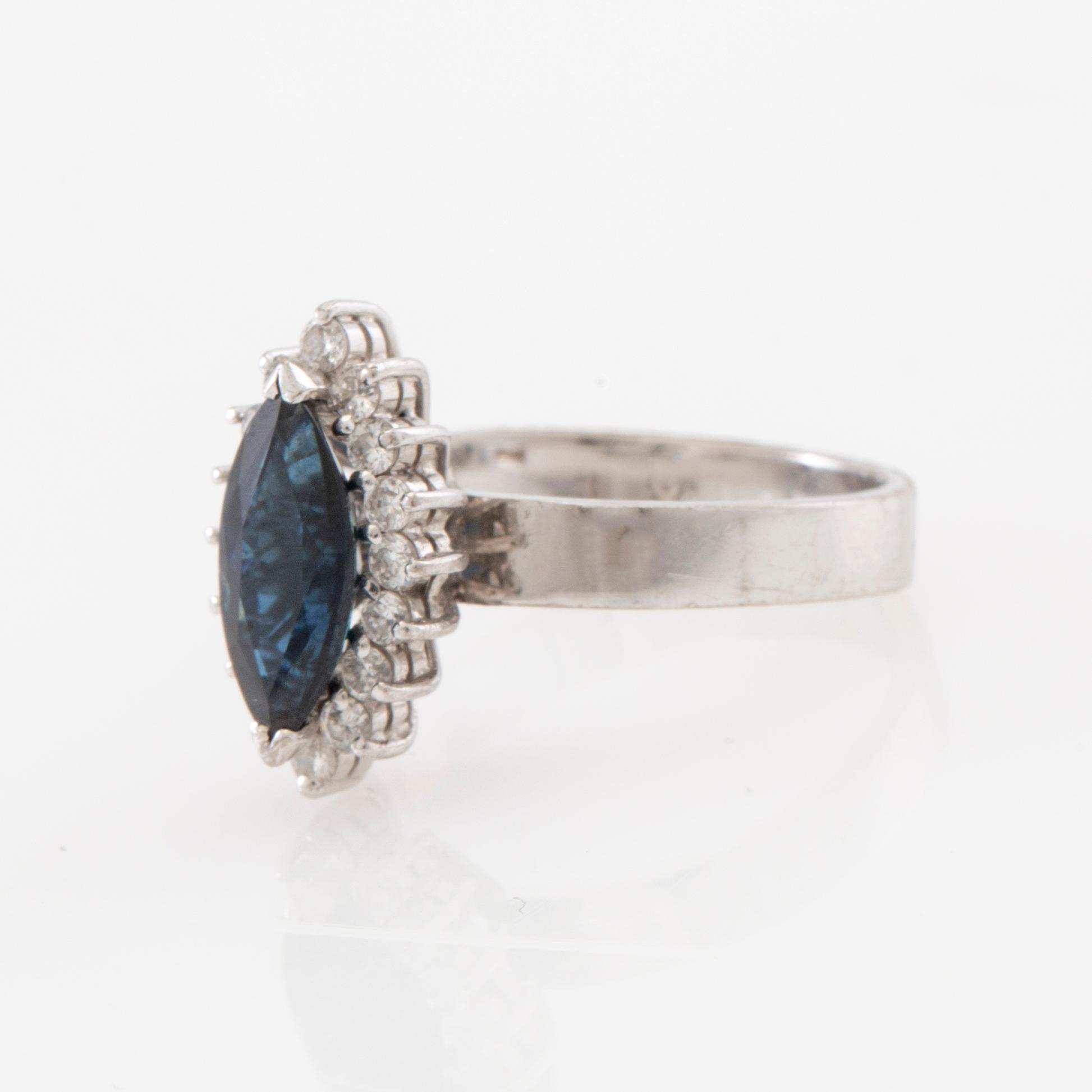 Ring 18K white gold set with a navette-cut sapphire and round brilliant-cut diamonds.