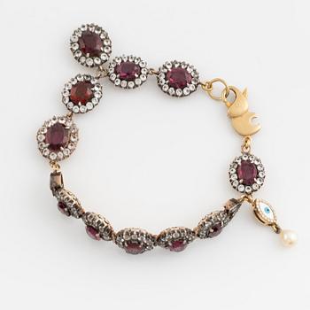 Bracelet with garnets and white stones, two charms, one eye enamel with brilliant cut diamonds, possibly oriental pearl.