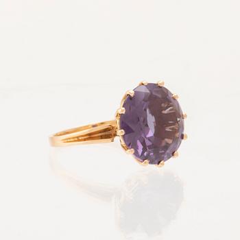 An 18K gold ring set with a round faceted colour-changing synthetic purple sapphire, Heribert Engelbert Stockholm.