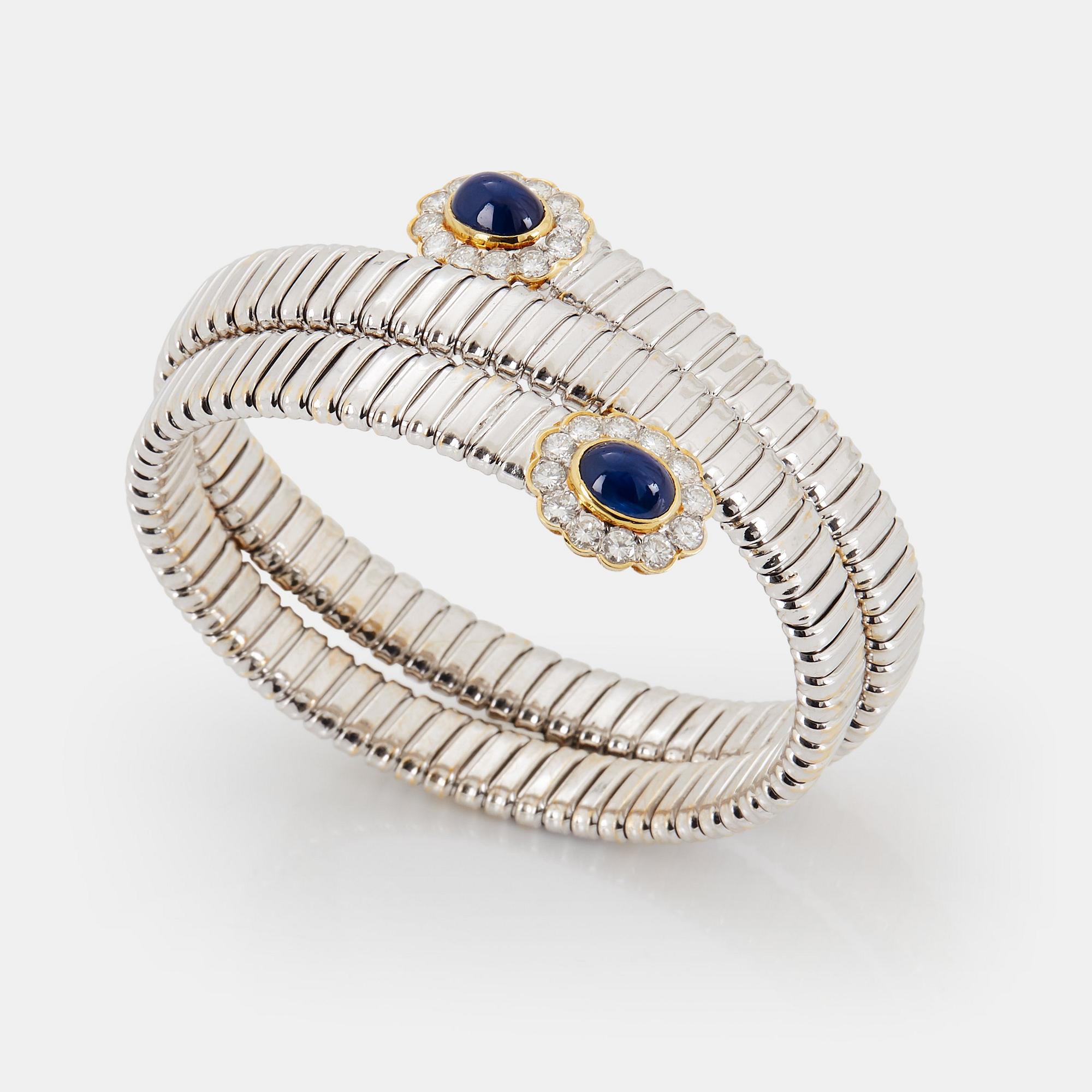 An 18K gold bangle set with cabochon-cut sapphires and round brilliant-cut diamonds.