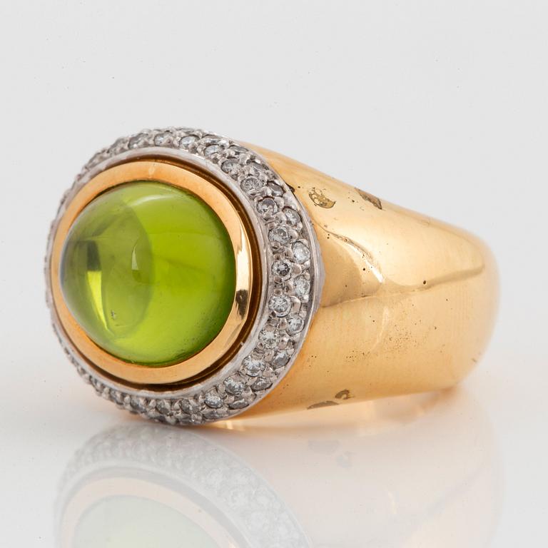 An 18K gold Steinlin ring set with a cabochon-cut peridot and round brilliant-cut diamonds.