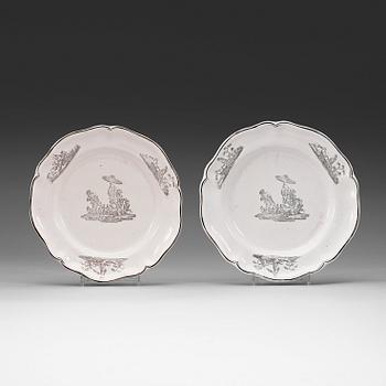 A set of two Marieberg faience dinner plates decorated in grisaille, dated 1740 and 1770.