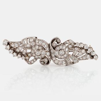 A double clip-brooch in platinum set with round brilliant-, emerald- and eight-cut diamonds.