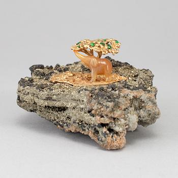 A sculpture of an agate elephant under a gilt three with inlays of tsavorites on rock formation, unmarked, 20th Century.