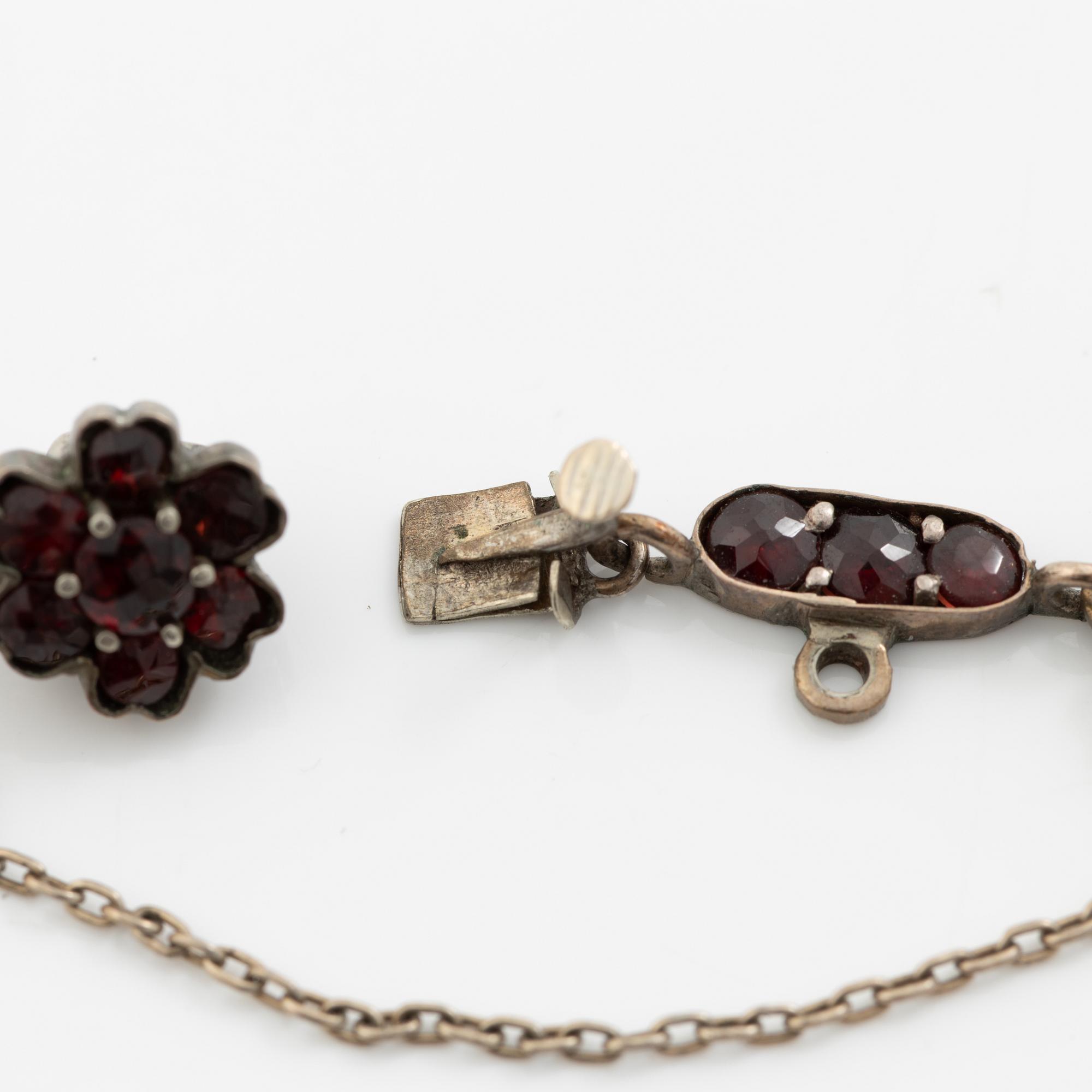 Garniture, necklace/bracelet and earrings in silver with garnets in the form of floral motifs, around the turn of the 20th century.