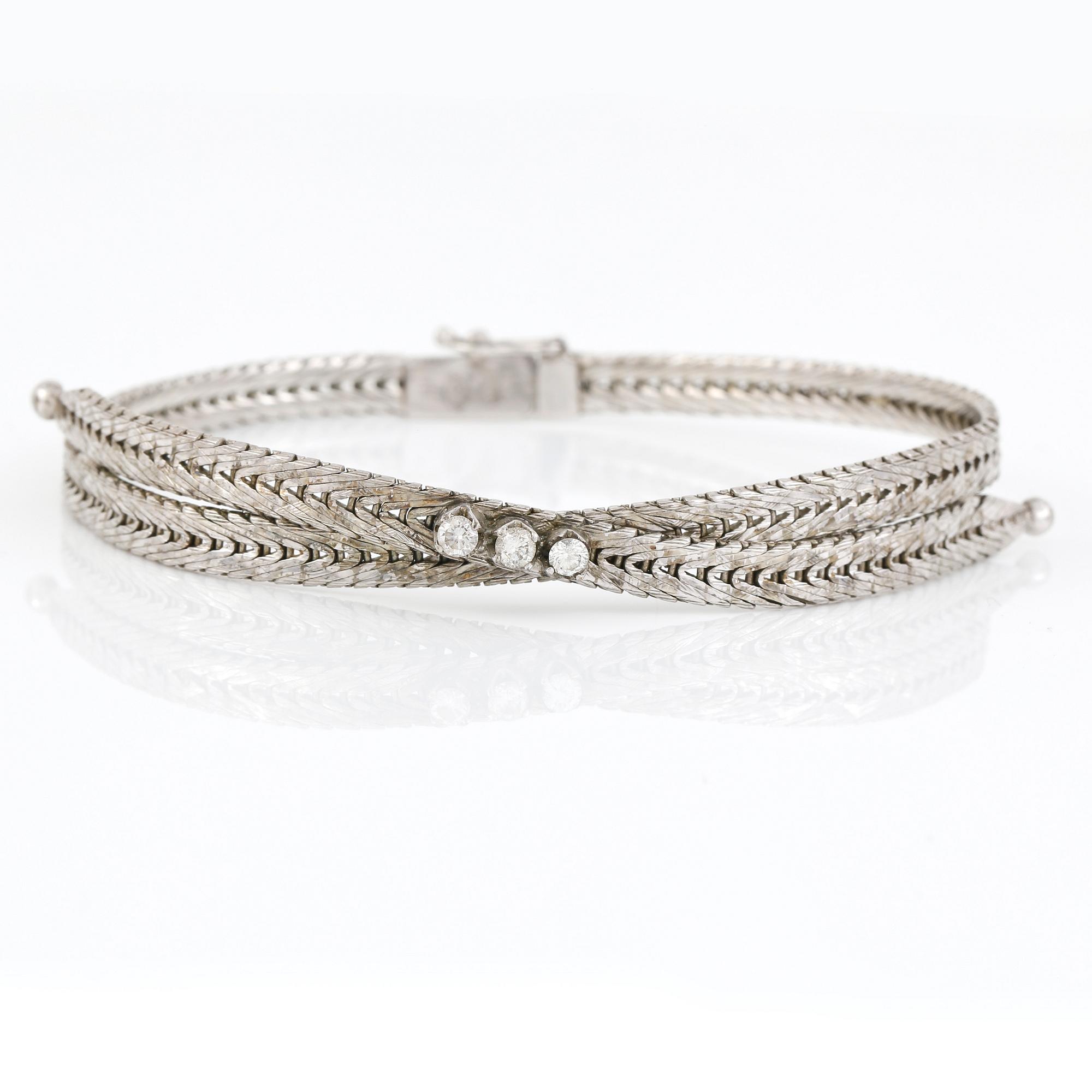 ARMBAND, 18K vitguld med 3 briljantslipade diamanter, tot ca 0,20 ct. Vikt 17,99 g.