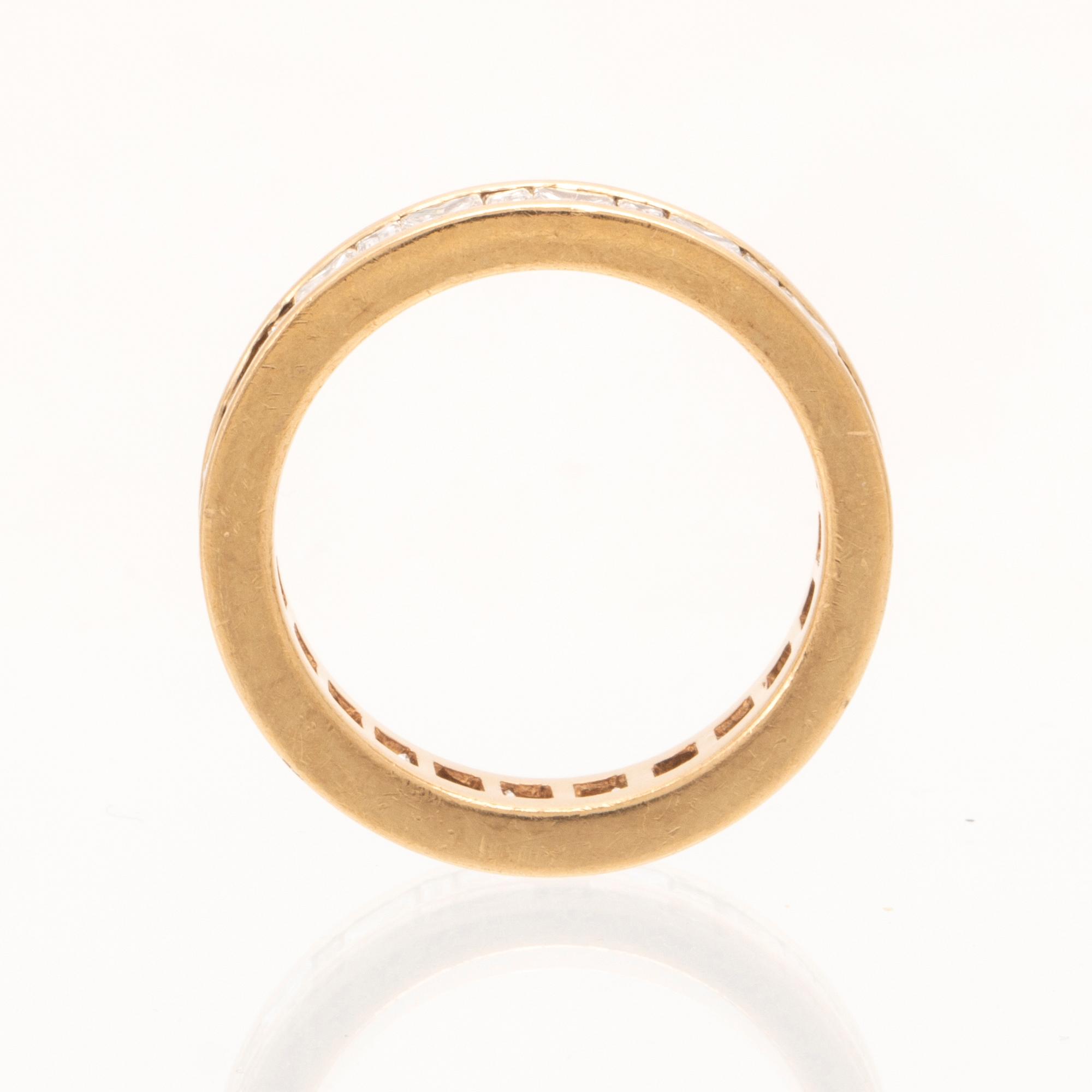 An 18K gold eternity ring set with baguette and princess cut diamonds by Hartmann's Denmark.