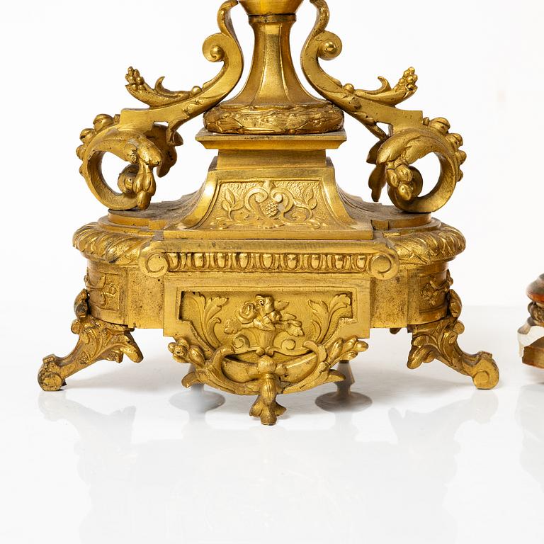 A mantle clock and a pair of candelabra, Louis XVI style, ca 1900.