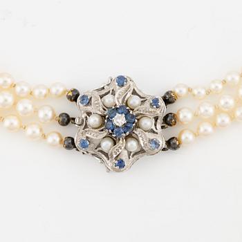 Pearl necklace, three-stranded, with graduated cultured pearls, clasp in 18K white gold with sapphires, pearls, and a brilliant-cut diamond.