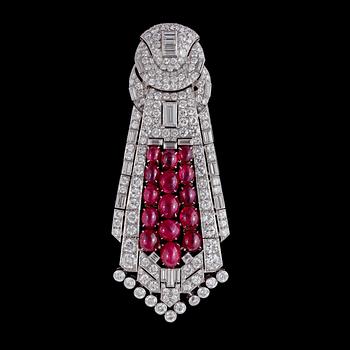 1031. HÄNGE/BROSCH, cabochonslipade rubiner, tot. ca 39.50 ct, smaragd- och briljantslipade diamanter, ca 23 ct. 1930-tal.