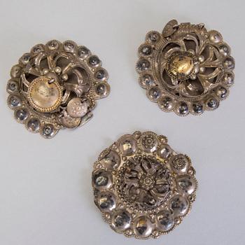 A collection of mostly silver, tradition folk buttons and belt buckles.