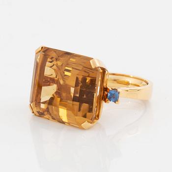 An 18K gold ring set with a faceted citrine and two sapphires.