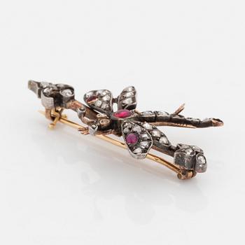 A silver and gold brooch set with rose-cut diamonds and cabochon-cut rubies.