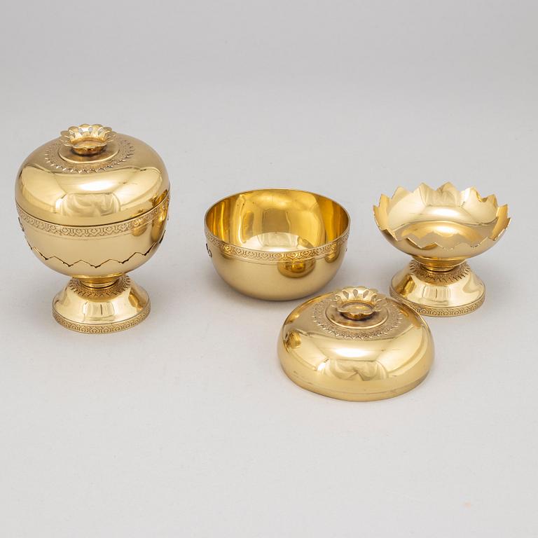 A set of eight polished brass pomme granate shaped jars with covers on stands, Marked Siam, Amfar Co.
