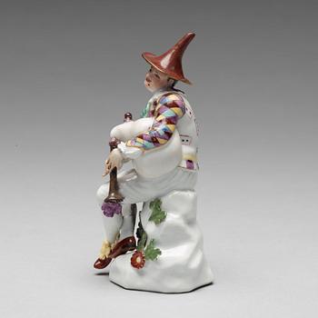A porcelain figure of harlekin playing the bagpipe, circa 1900.