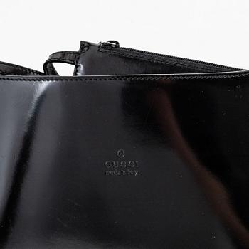 Gucci, a black, patent leather handbag.