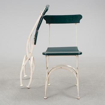 A pair of cast iron chais with wooden seats and a cast iron table, early 20th century.