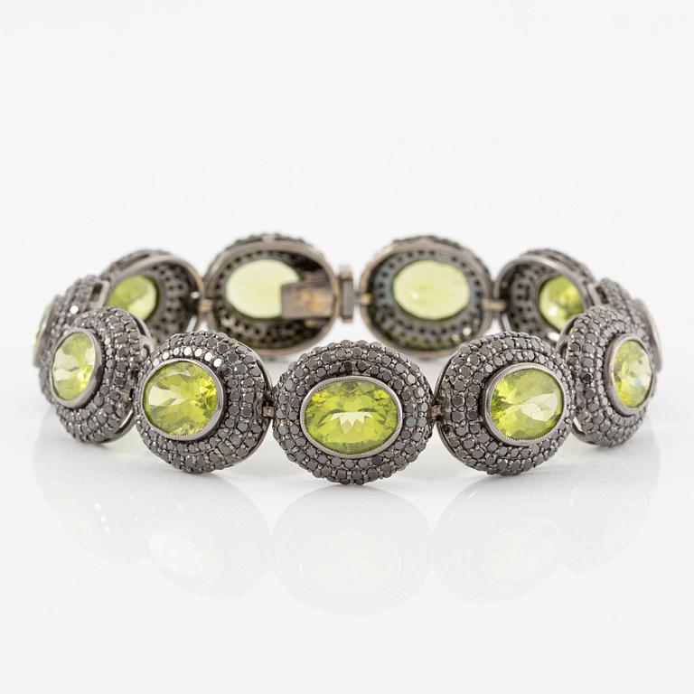 Bracelet in 18K gold with oval peridots and brilliant-cut black diamonds.