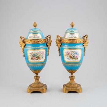 A pair of pordelain and gilt brass urns in teh style of Sevres, 20th Century.