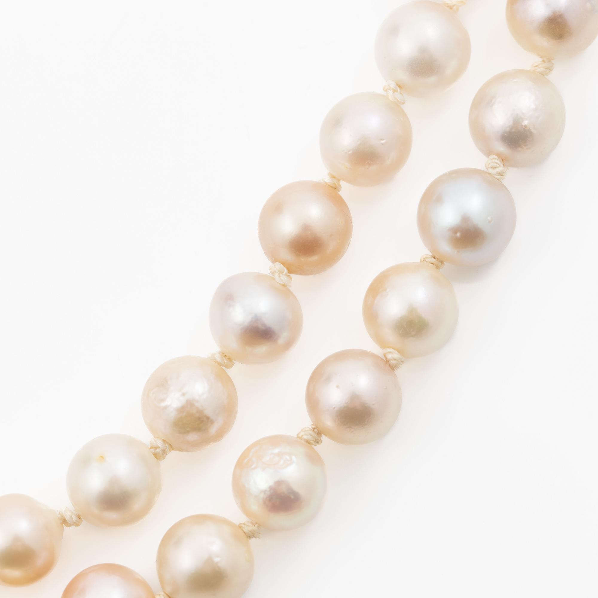 Long cultured pearl necklace with an 18K white gold clasp set with emeralds.