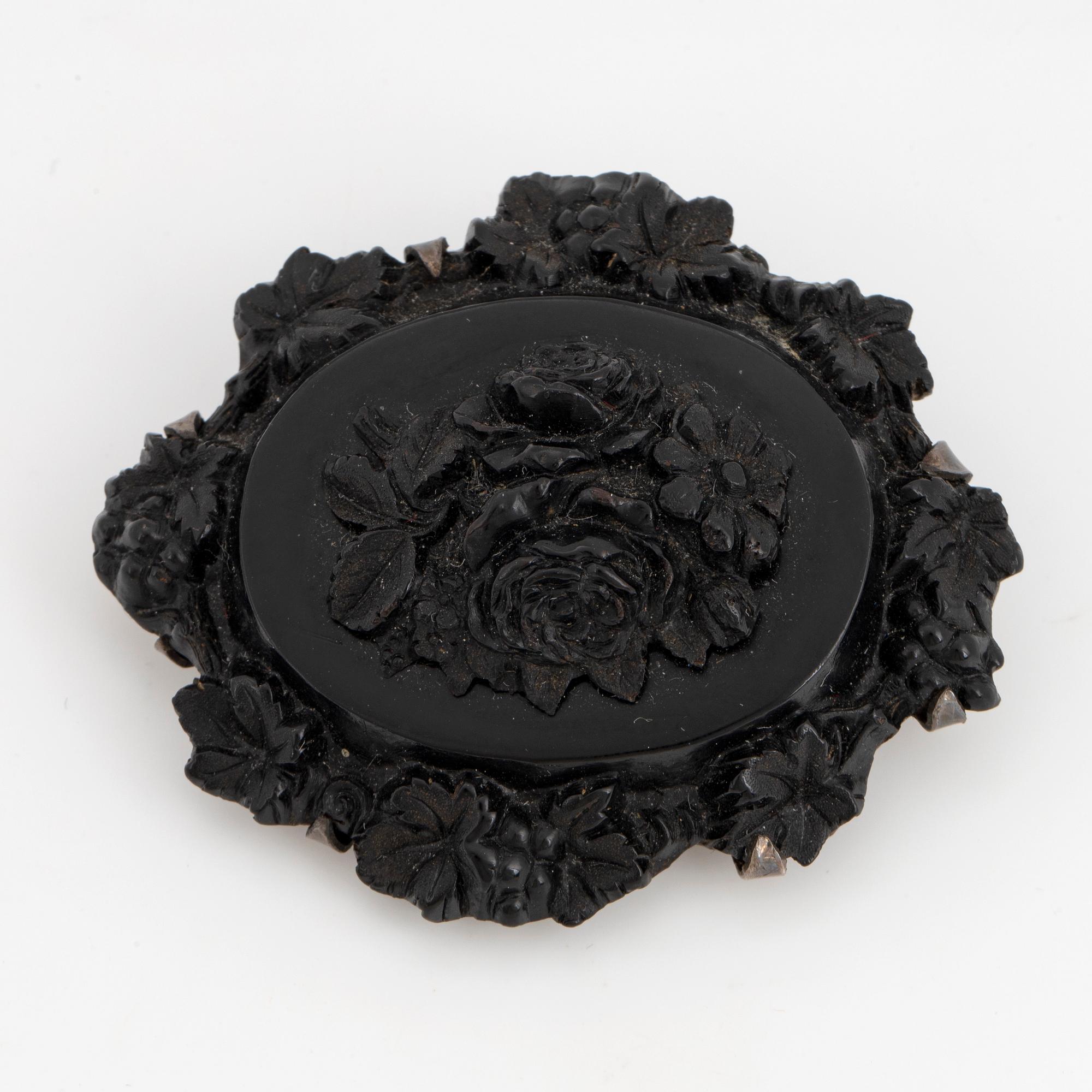 Carved possibly jet/coal and silver brooch.