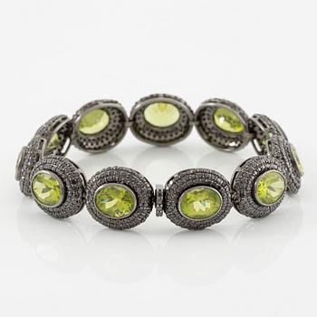 Bracelet in 18K gold with oval peridots and brilliant-cut black diamonds.