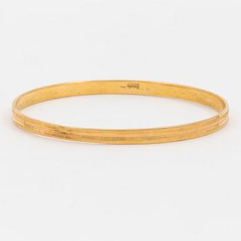 A bangle with a textured surface. 14K gold.