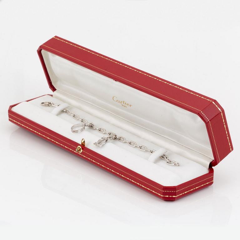 An 18K white gold Cartier "Spartacus" bracelet with two charms.