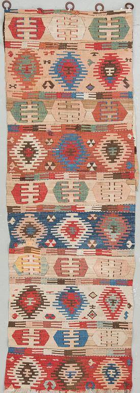 An antique Anatolian kilim fragment in form of a drape, around 232 x 76 cm.